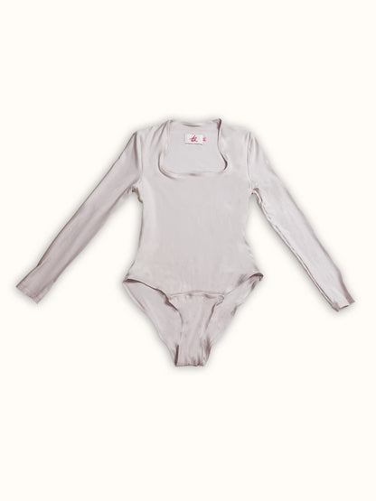 A long-sleeve jersey bodysuit made from deadstock fabric, featuring a square neckline and front snaps. A made-to-order piece